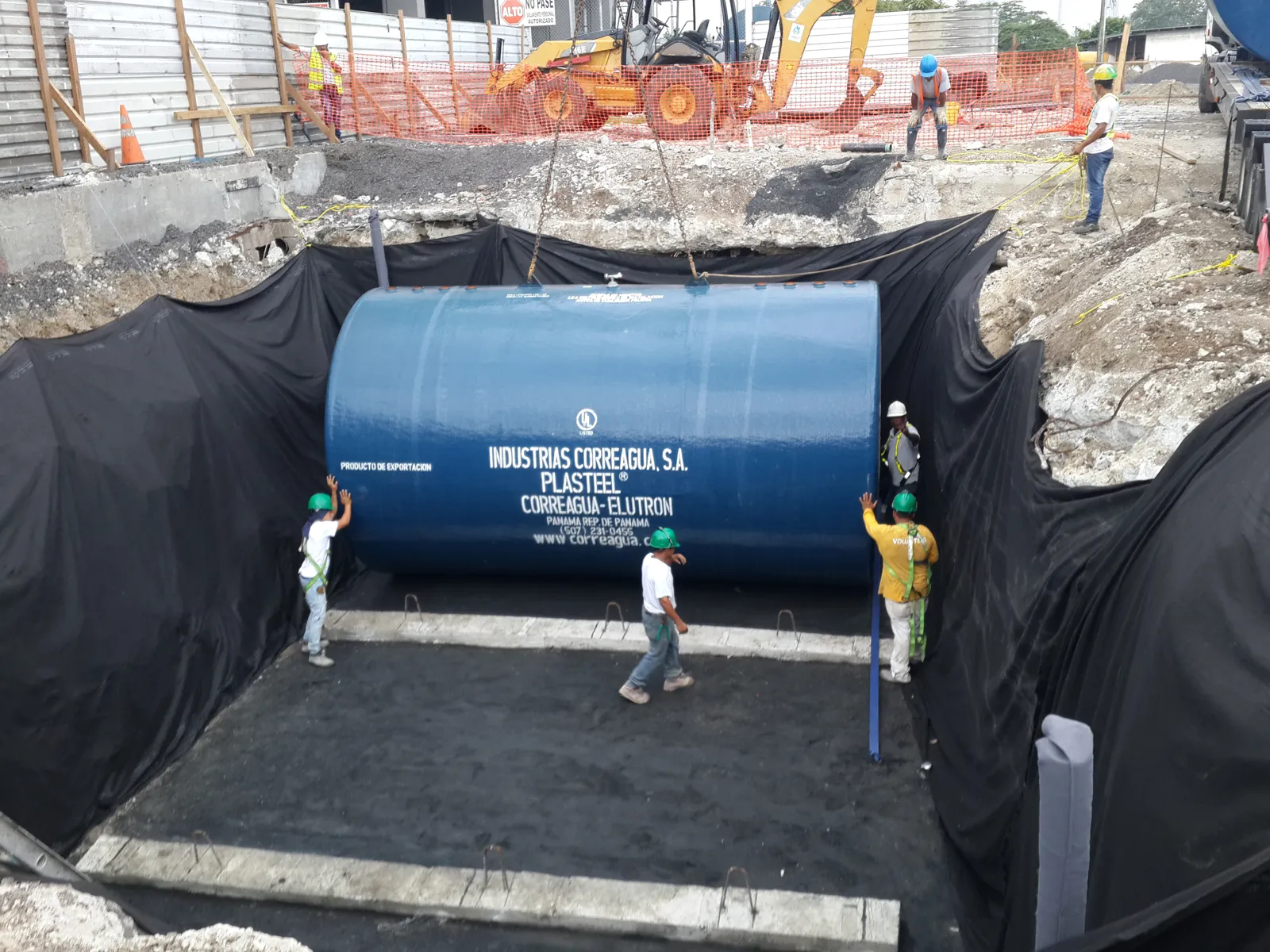 Tanque PLASTEEL azul dentro de la fosa con membrana y técnicos alrededor