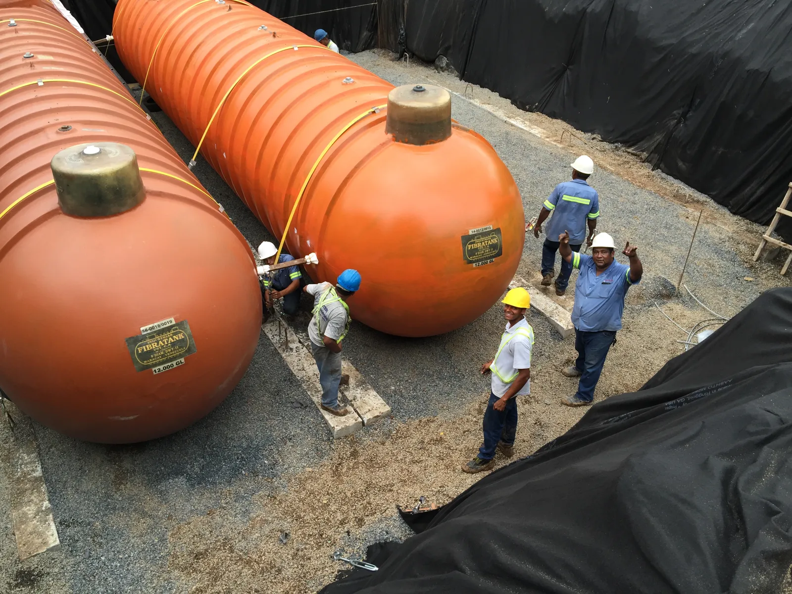 Cuadrilla de técnicos con casco entre los tanques dentro de la fosa
