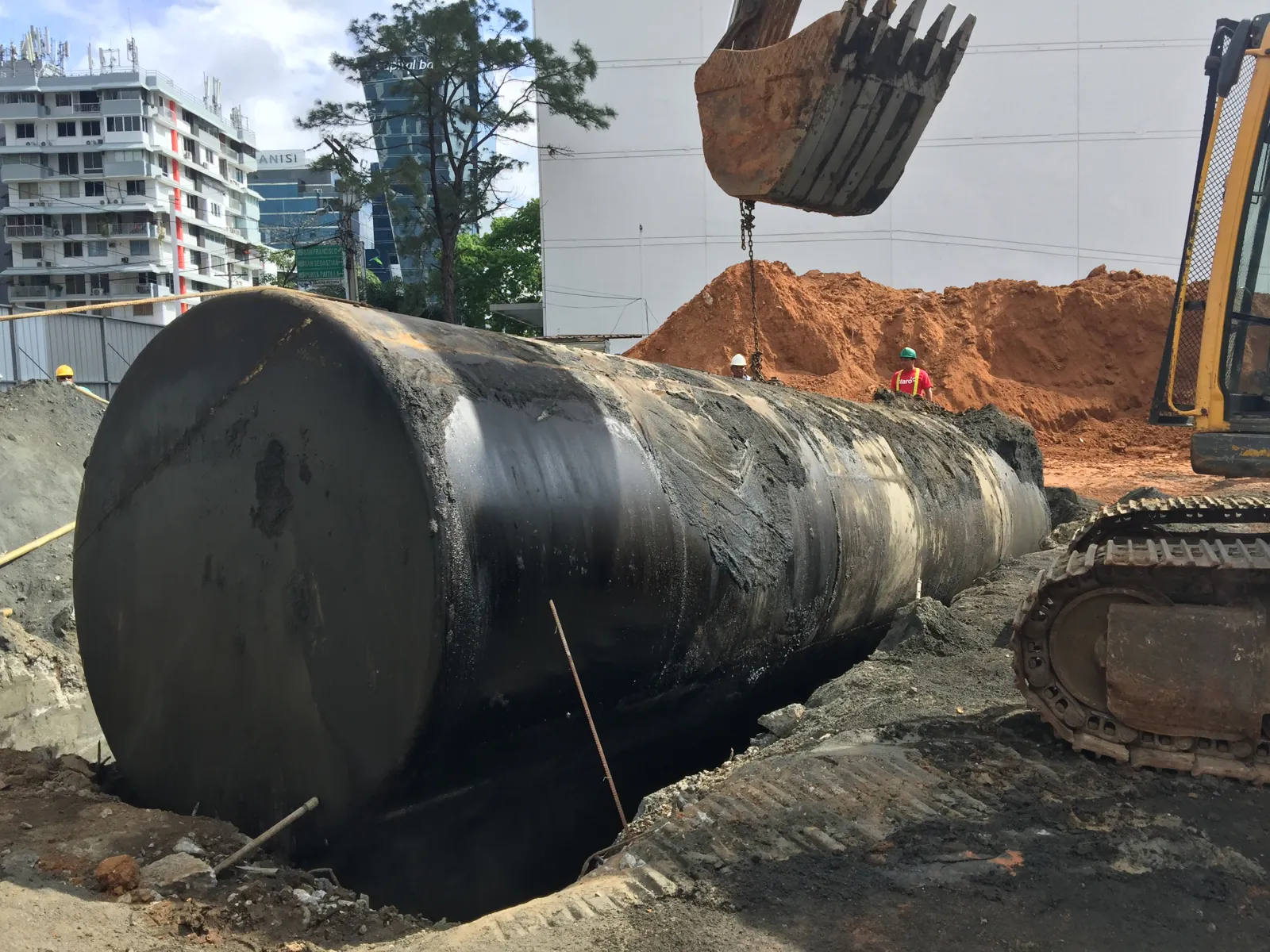 Excavadora retirando un tanque de acero viejo de la fosa