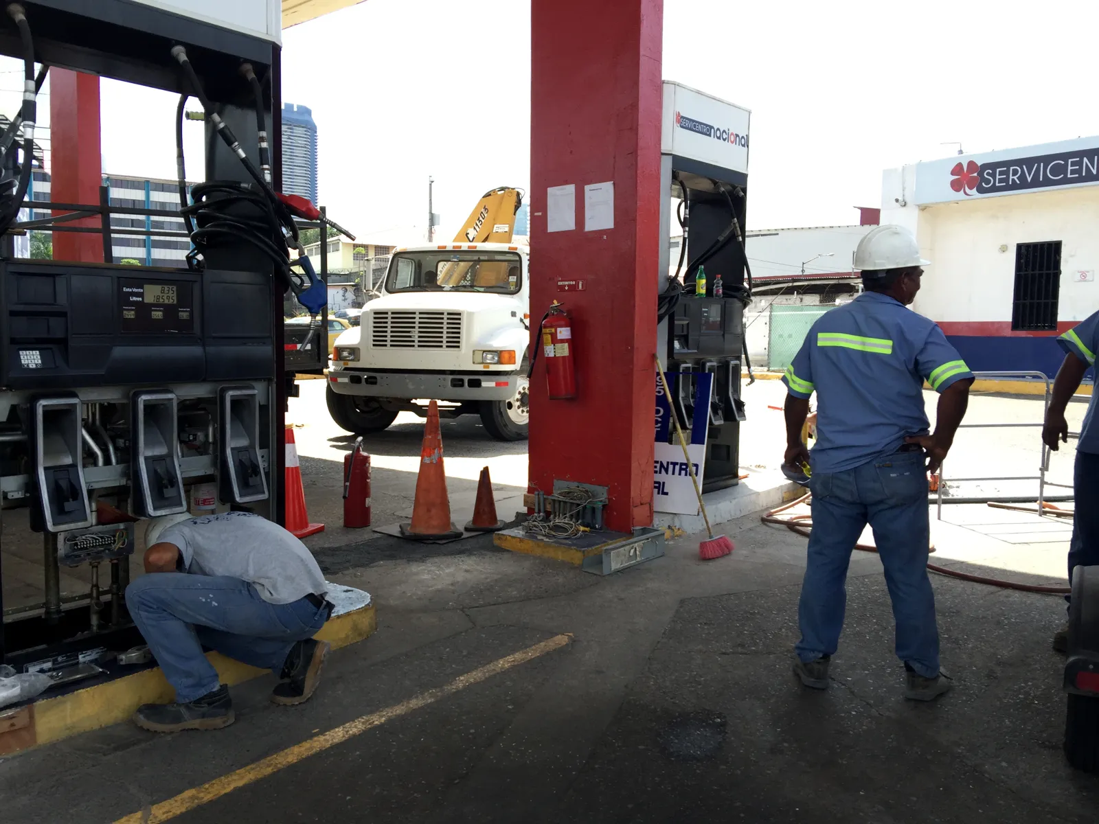 Técnicos trabajando en el dispensador junto al camión grúa