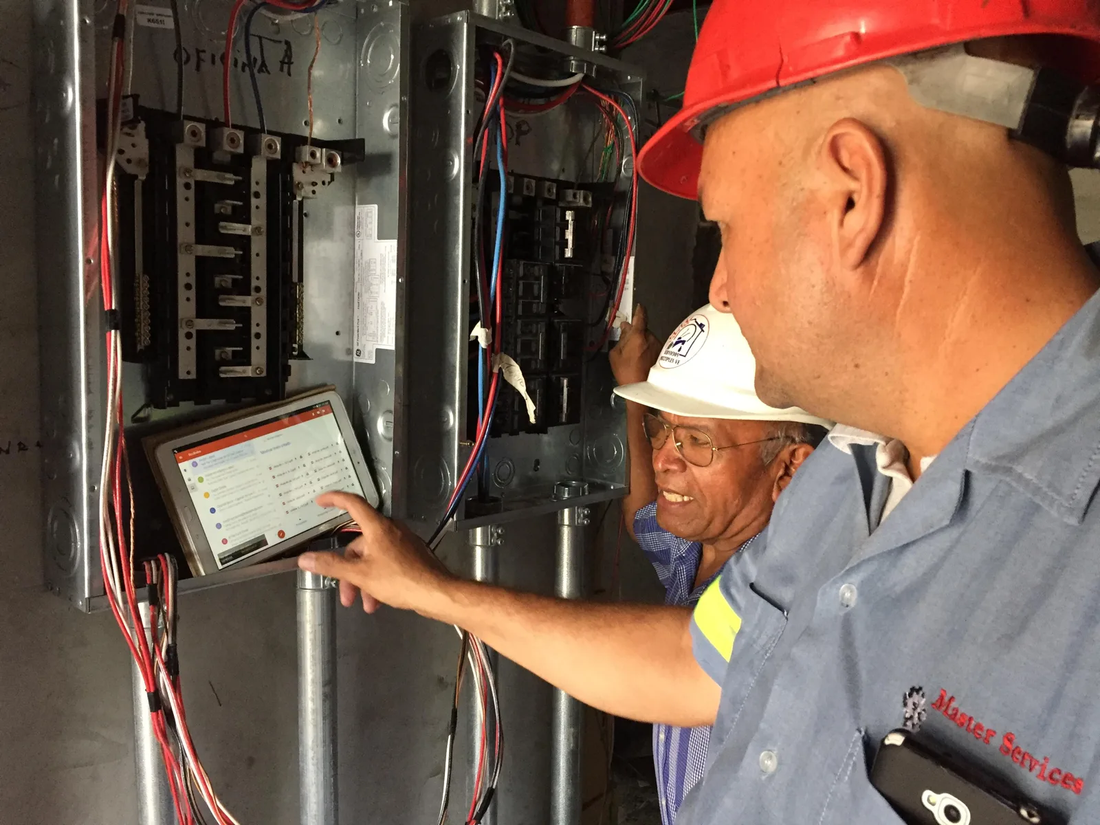 Técnico con casco midiendo un tablero eléctrico con un equipo de diagnóstico