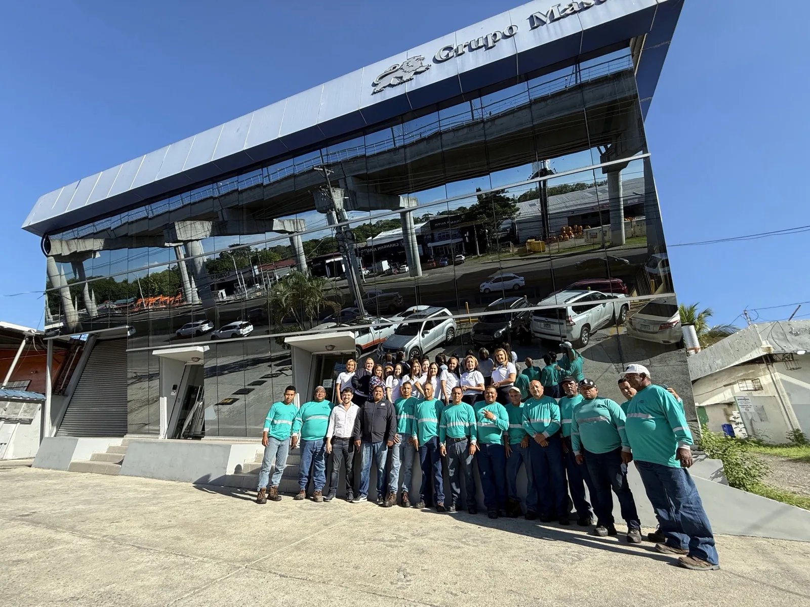 Equipo de Master Services — técnicos en uniforme teal y personal administrativo en la sede de la empresa, un edificio moderno con paredes de vidrio en la Ciudad de Panamá